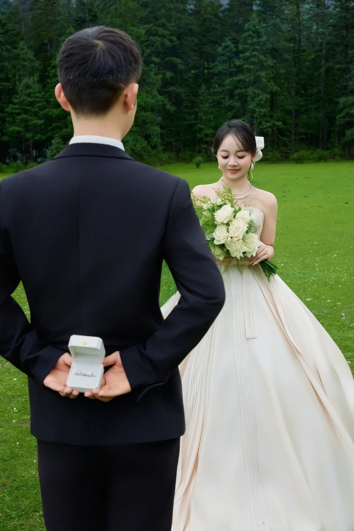 草坪上，新郎手藏戒指盒走向捧花的新娘